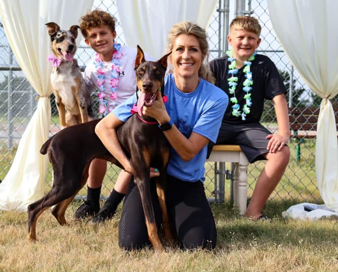 woman and two children smile while posing with their two dogs